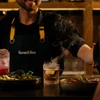 Person serving a couple cocktails and plates of food at the bar