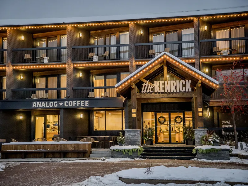A snowy hotel exterior and café illuminated by its window light
