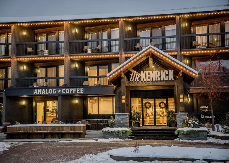 A snowy hotel exterior and café illuminated by its window light