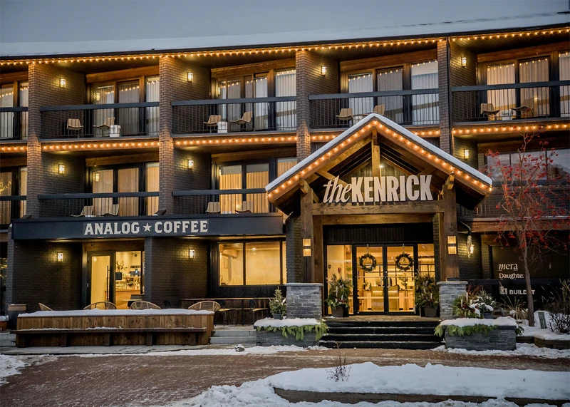 A snowy hotel exterior and café illuminated by its window light