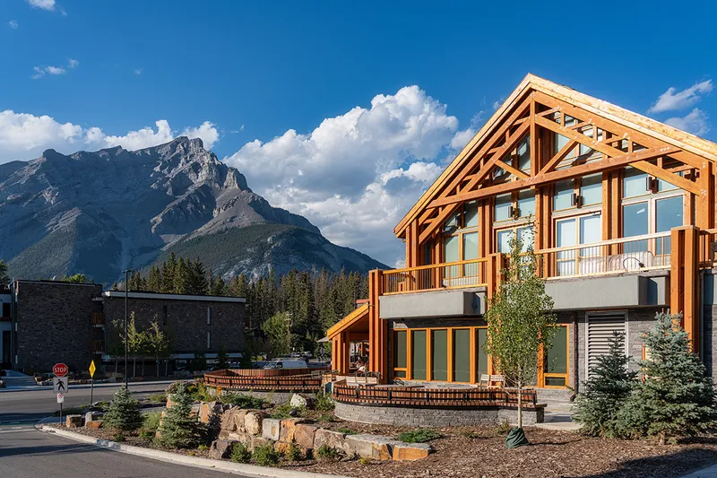 Detail of The Otter Hotel's wood and glass exterior with a mountain backdrop